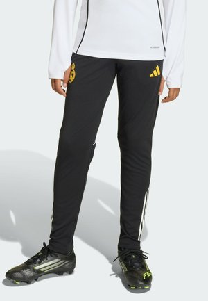 Black athletic pants with a slim fit, featuring white side stripes and a yellow club logo. Made from smooth, flexible material.
