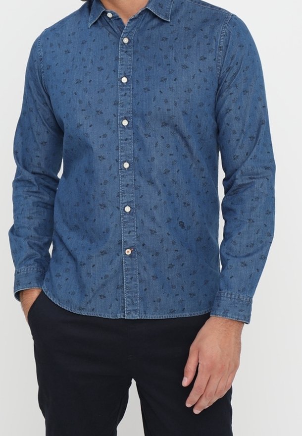 Camisa de mezclilla de color azul oscuro con un sutil patrón floral, que presenta un cierre de botones en la parte delantera, cuello y mangas largas. Tejido texturizado.