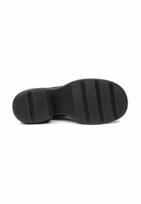 Suela de zapato de goma negra con una superficie texturizada. Presenta ranuras horizontales y un borde redondeado. Diseñada para tracción y estabilidad.