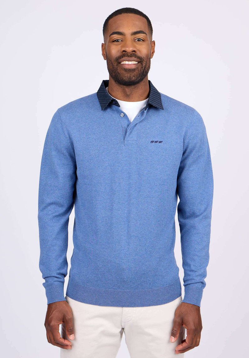 Polo à manches longues bleu avec un tricot texturé. Présente un col boutonné avec un motif à pois sombre et un logo brodé sur la poitrine.