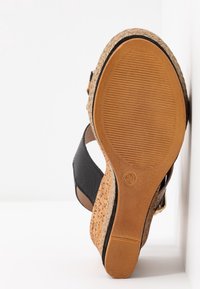 Sandale compensée avec semelle en caoutchouc texturé, brides en cuir noir et semelle en style liège, taille 38, positionnée avec la semelle tournée vers l'avant.