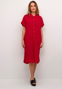 Vestito camicia rosso con bottoni, colletto, maniche corte e spacchi laterali; realizzato in tessuto testurizzato, presenta una vestibilità ampia e un taglio dritto.