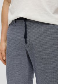 Pantalone u mornarsko plavoj kockastoj kombinaciji s teksturiranom tkaninom, s elastičnim strukom i vezicom za prilagodljivo pristajanje.