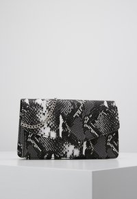 Clutch negro y blanco con patrón de piel de serpiente, con cadena plateada, forma rectangular, superficie texturizada y cierre de solapa.