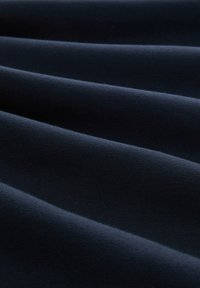 Tissu bleu marine foncé avec des plis doux et parallèles créant des ombres douces et de la texture.