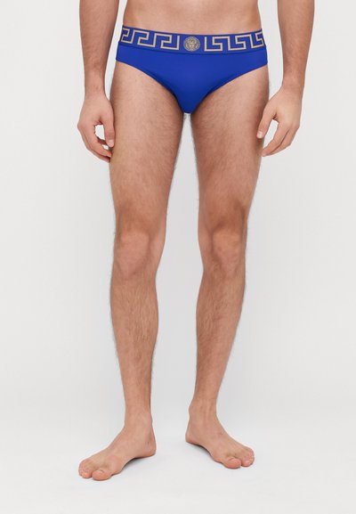 Shorts de bain bleus avec une ceinture en clé grecque dorée et un emblème, texture lisse, design ajusté, sans motifs ni accents supplémentaires.