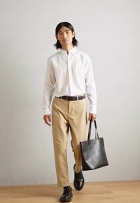 White button-up shirt, beige trousers, black leather shoes, and a black tote bag. Simple design, smooth texture, and neutral colors.
