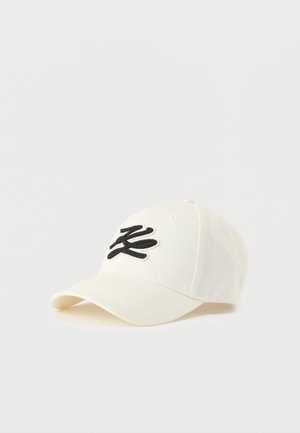 Casquette de baseball blanche à visière courbée avec un "K" stylisé noir brodé sur le panneau avant.