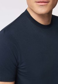 Marineblauwe, kortarmige t-shirt gemaakt van een gladde stof. Bevat een klassieke ronde halslijn en subtiele stikdetails.