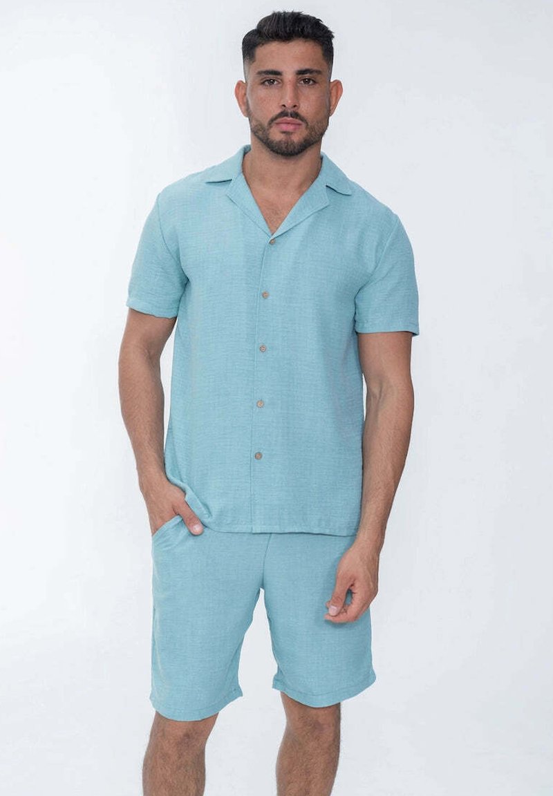 Chemise à manches courtes bleu clair avec boutons et shorts assortis en tissu texturé. Présente un col évasé et des poches avant.