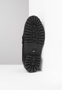 Semelle de chaussure en caoutchouc noir présentant un motif de bande de roulement avec des formes croisées en relief et un texte indiquant "Nero Giardini MADE IN ITALY" en accents de couleur.