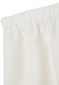 Tejido blanco con una superficie texturizada, que cuenta con un borde superior elástico fruncido para facilitar su colgado. Caída suave sin patrones ni acentos.