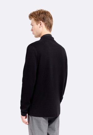 Maglione nero lavorato a maglia con collo a camicia, maniche lunghe e vestibilità comoda. Texture liscia, design minimalista e nessun ornamento visibile.