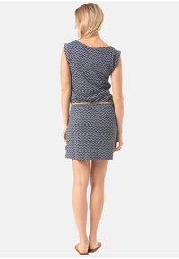 Modré šaty s bílým zigzagovým vzorem, krátké rukávy a vypasovaný pas. Obsahují dekorativní pásek a rovný střih.