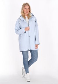 Šviesiai mėlyna vandeniui atspari striukė su kapišonu, priekyje užtrauktuku ir mygtukais. Savybės: dvi šoninės kišenės ir elastinės virvelės ant kapišono.