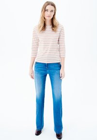 Gestreiftes Langarmshirt in Hellrosa und Weiß. Blaue gerade Jeans mit ausgewaschenem Finish. Braune Knöchelstiefel mit glatter Oberfläche.