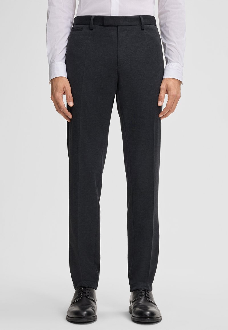 Dunkelgraue, maßgeschneiderte Hose mit glatter Textur, taillierter Passform, flacher Vorderseite und einem dezenten Muster, kombiniert mit schwarzen Schuhen.