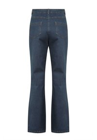 Ciemnoniebieskie jeansy bootcut z dwoma tylnymi kieszeniami i wysokim stanem, pokazane od tyłu na białym tle.