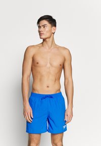 Shorts de bain bleus avec taille élastique à cordon, en tissu léger, et détail du logo sur la jambe gauche. Couleur unie, design jusqu'aux genoux.