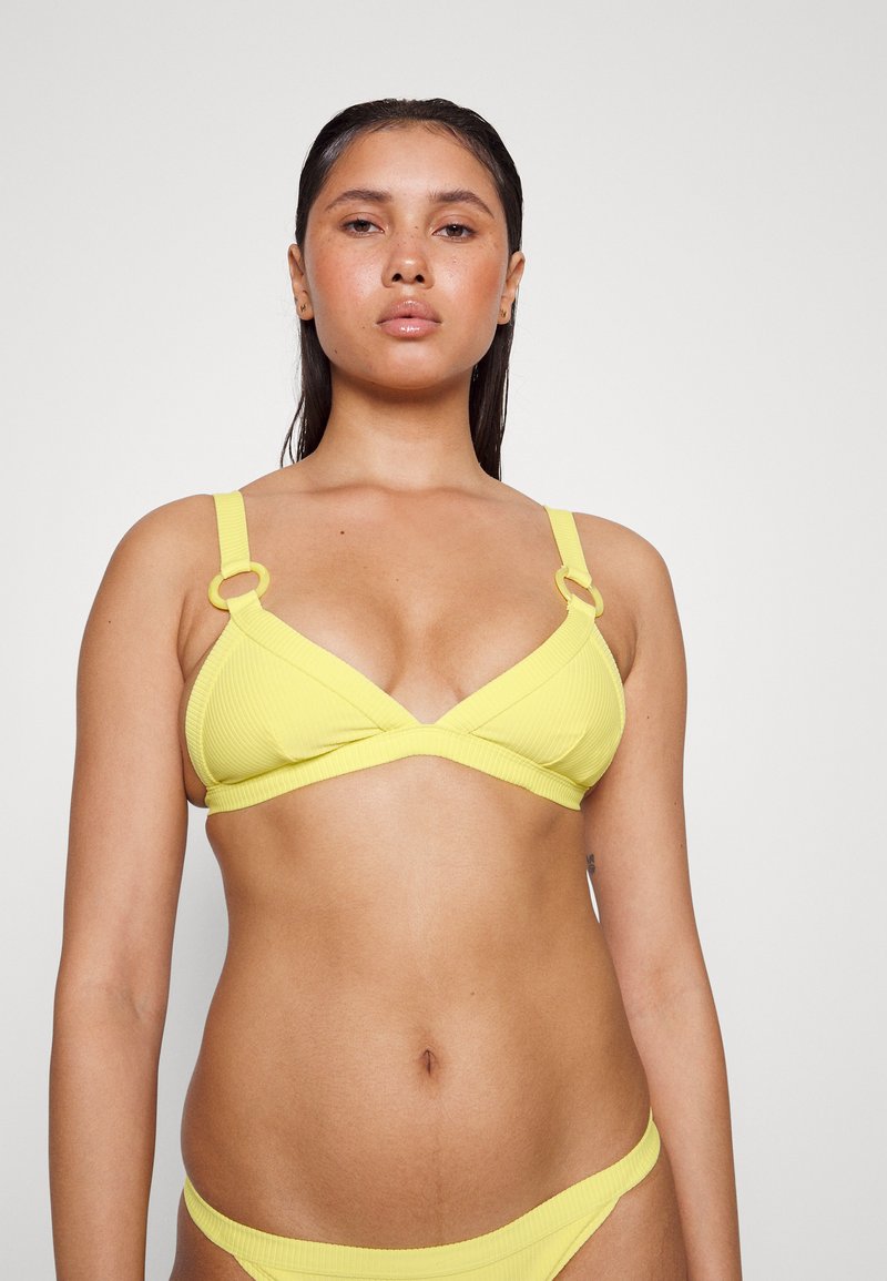 Conjunto de bikini amarelo com nervuras, apresentando um top triangular com alças largas e argolas metálicas, combinado com um fundo de cintura baixa correspondente.