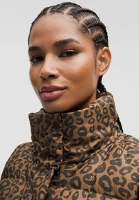 Brun pufferjakke med leopardmønster. Høj krave, blank overflade og trykknaplukning.