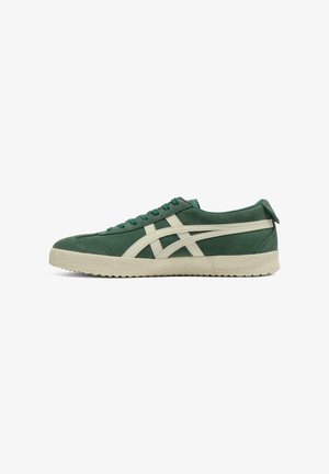 Sneaker verde in suede con strisce crema, suola in gomma texturizzata, punta rotonda e lacci piatti. Presenta un piccolo tassello sul tallone per una facile calzata.