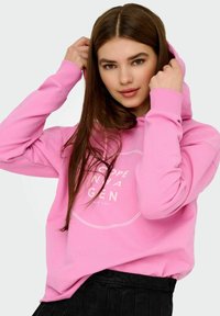 Rosa hoodie gjord av mjuk bomullsblandning, med en framtida grafiskt tryck med text, långa ärmar och en dragkedja huva.