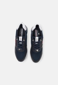 Baskets bleu marine avec empeigne en mesh, accents blancs et semelle noire. Elles comportent des lacets, un logo sur la languette et des détails texturés sur les côtés.