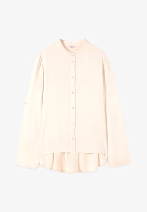 Kremowa bluzka z długim rękawem, okrągłym kołnierzykiem, guzikami z przodu, luźnym fasonem i lekko zakrzywionym dołem, który jest dłuższy z tyłu.