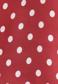 Czerwony materiał z równomiernie rozmieszczonymi białymi kropkami, ukazujący szczegóły struktury i wzoru.