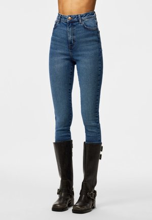 Blå høj talje skinny jeans kombineret med sorte knæhøje læderstøvler med side spænder.