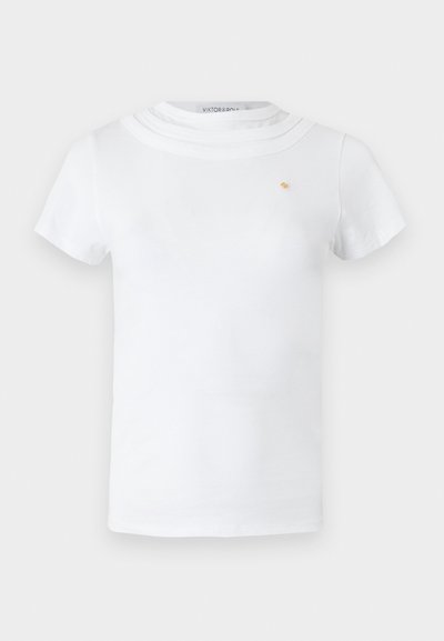 T-shirt blanc à manches courtes avec un col rond superposé et un petit emblème doré sur la poitrine gauche.