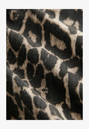 Fekete és bézs szövet leopárd mintával, amely texturált, szőtt rostokat és eltérő foltokat tartalmaz a felületen.