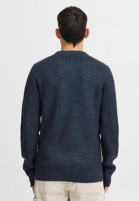 Dark navy ribbed knit sweater with a round neckline and long sleeves, featuring a textured finish and a straight hem.