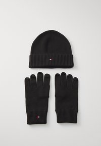 Gorro de punto negro con un dobladillo, acompañado de guantes negros a juego. Cada artículo presenta un pequeño acento de logotipo de color.