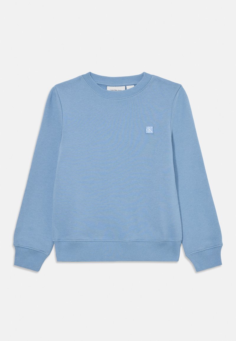 Světle modrý svetr s kulatým výstřihem, žebrovanými manžetami a lemem. Na hrudi se nachází malé logo na patce. Vyrobeno z měkké směsi bavlny.