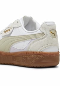 Weiße Leder-Sneaker mit hellbeigen Akzenten und einer strukturierten beigen Wildlederspitze. Verfügt über eine braune Gummisohle und ein goldfarbenes Logodetail.