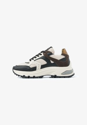 Chunky low-top sneaker with black, white, brown leather, mesh panels, black laces, and thick textured sole with visible heel cushioning.