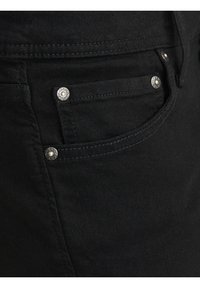 Černé džíny z denimu se stříbrnými kovovými doplňky, včetně nýtků a švů, s přední kapsou a hladkou texturou.