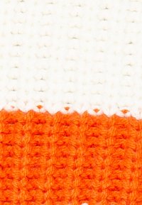 Pletená látka s třemi horizontálními pruhy: bílým, oranžovým a jasně oranžovým, s texturovaným, žebrovaným vzhledem a vlnitým okrajem.