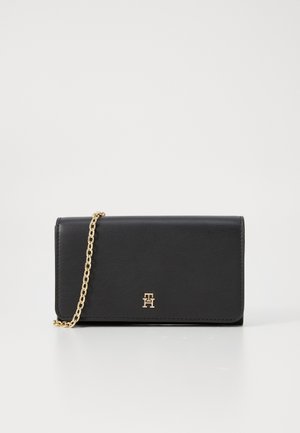 Black leather wallet with gold chain strap, featuring a prominent embossed logo on the front. Smooth texture and minimalist design.