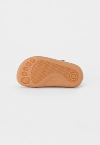 Braune Gummisohle mit strukturiertem Grip, versehen mit einem Fußabdruckdesign, wellenförmigen Linien und dem eingeprägten Markennamen "freddo BAREFOOT".