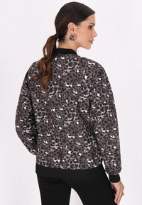 Jachetă bomber cu imprimeu de leopard în nuanțe de gri și negru, având un tiv și manșete ribbate, cu o croială confortabilă și o textură netedă.