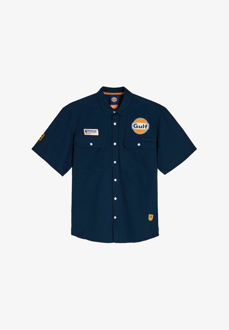 Granatowa koszula z krótkim rękawem wykonana z bawełny, z dwiema kieszeniami z przodu, logo Gulf i żółtymi akcentami na rękawie oraz dolnym brzegu.
