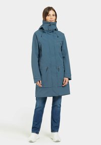 Parka bleue imperméable avec col montant, poches zippées et cordons de serrage réglables. Dispose d'une coupe droite et de manches longues.