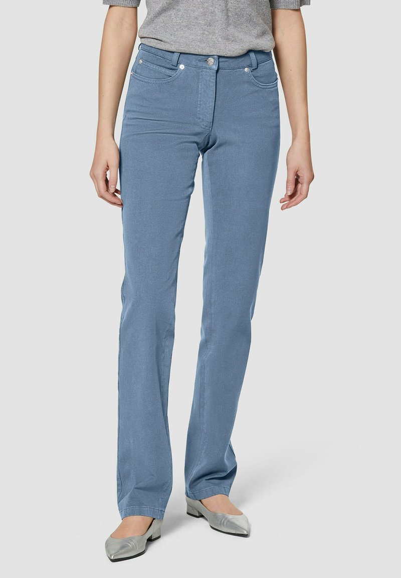 Lichtblauwe rechttoe-rechtaan jeans van zachte denim. Heeft voorzakken, subtiele stiksels en een middelhoge taille. Gepaard met zilveren ballerina's.