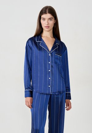 Set di pigiama in raso blu navy con strisce verticali bianche. Caratterizzato da una camicia con colletto e bottoni, dotata di taschino sul petto e pantaloni abbinati.