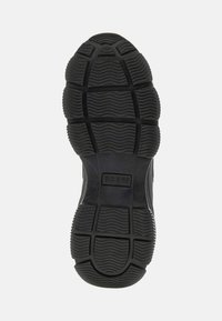 Black rubber shoe sole with textured tread pattern and "GUESS" brand logo embossed in the center.
