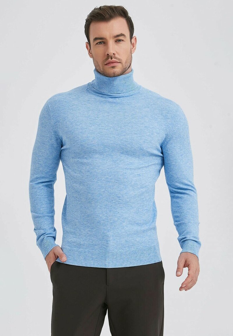 Pull à col roulé bleu clair avec une finition texturée, col et poignets c ôtelés, design ajusté, associé à un pantalon foncé.