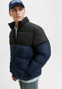 Kurtka pikowana z czarną górną częścią i granatową dolną częścią, z wysokim kołnierzem, zamkiem błyskawicznym i miękką, gładką fakturą.